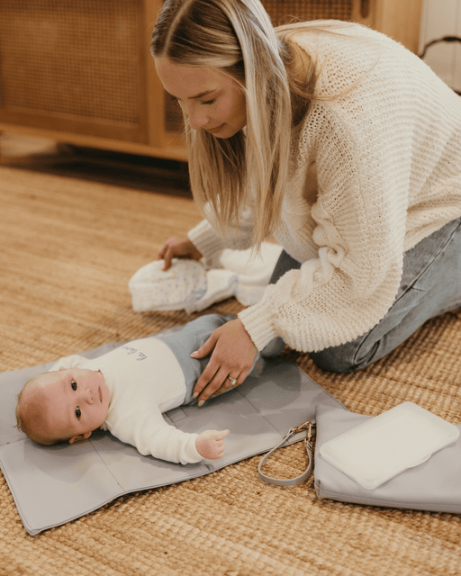 On the living room floor a mum changes her baby boy's nappy