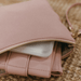 Spilling out of a pale pink nappy wallet are its contents: nappies, fold-up vegan change mat and a portable wipes case.